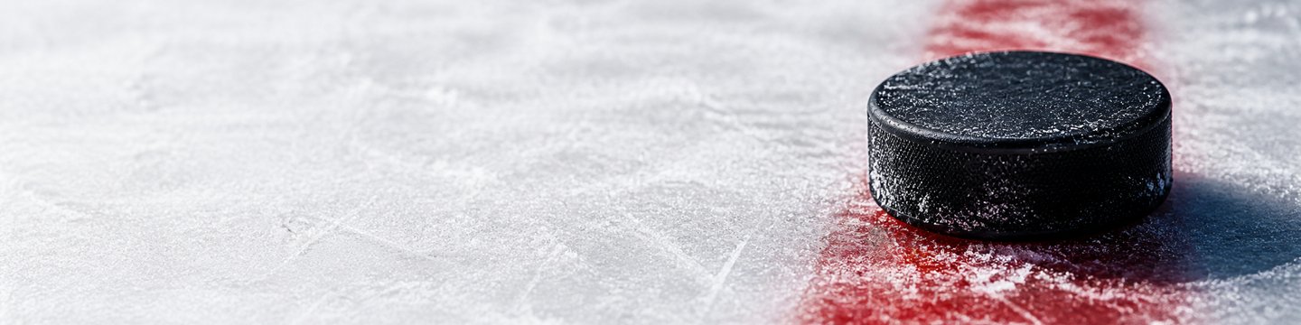 Hockey puck on ice beside a red marking